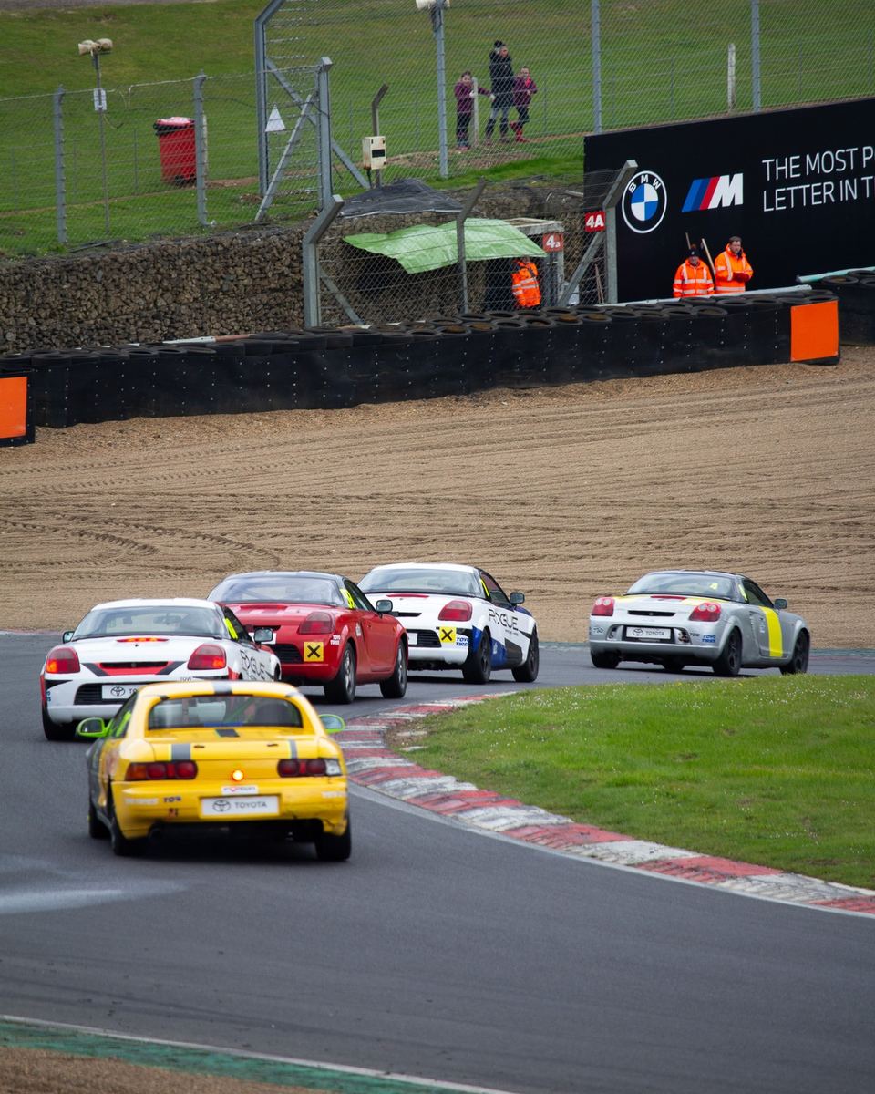 Classic cars racing around a bend at a motorsport circuit