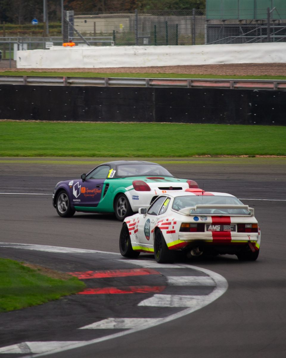Two race-liveried sports cars cornering on track